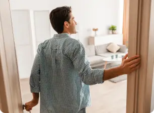 Homem olhando para uma sala de estar vazia com caixas de mudança.